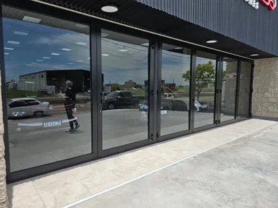 Paños fijos y puertas de aluminio negro en el lateral del salón de ventas