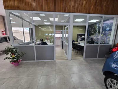 Oficinas internas cerradas con paños fijos de aluminio blanco en el salón