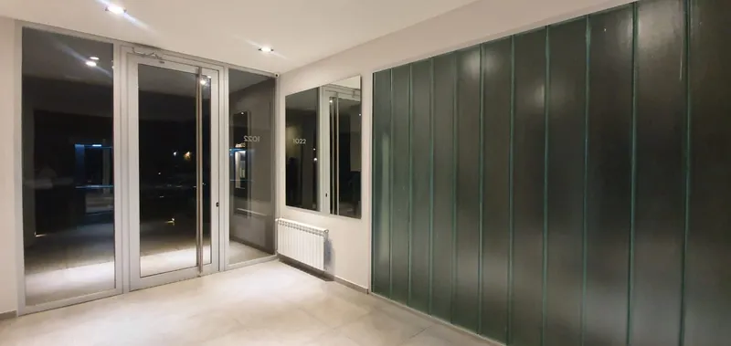 Puerta de aluminio con dos paños fijos a los laterales y pared de profilit