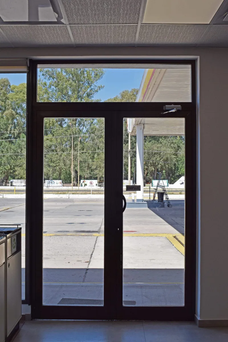 Puerta de doble hoja de aluminio bronce colonial en el acceso de la estación de servicio