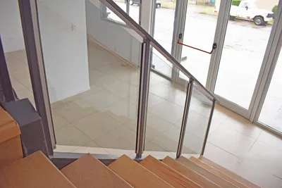 Baranda de cristal laminado gris junto a la escalera y los paños vidriados de la oficina