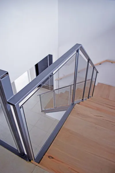 Baranda de cristal laminado gris con perfilería de aluminio en la escalera interna