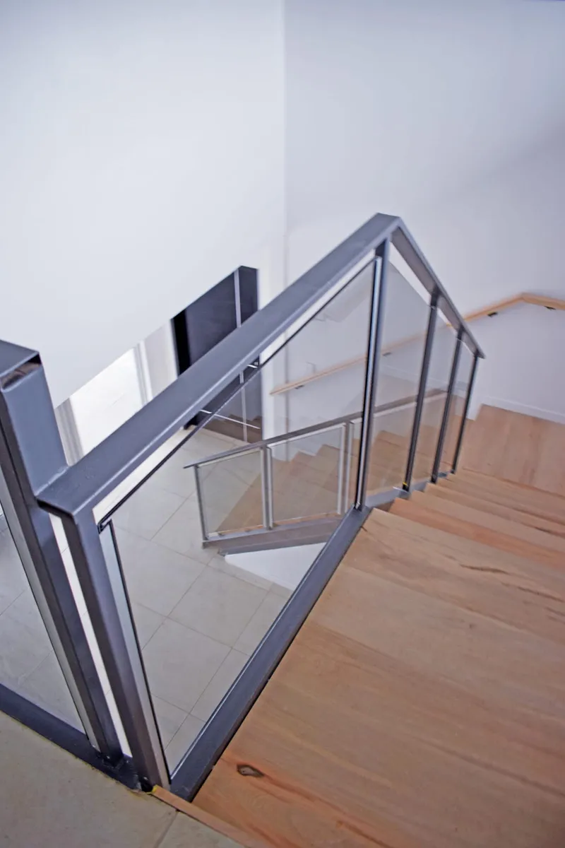 Baranda de cristal laminado gris con perfilería de aluminio en la escalera interna
