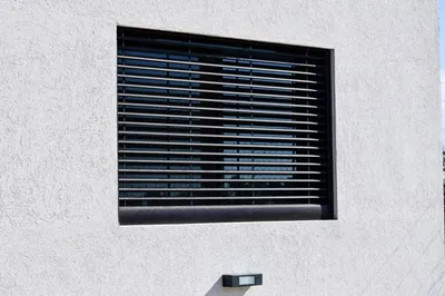 Celosía de aluminio anodizado negro sobre la ventana del dormitorio