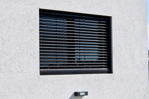 Celosía de aluminio anodizado negro sobre la ventana del dormitorio