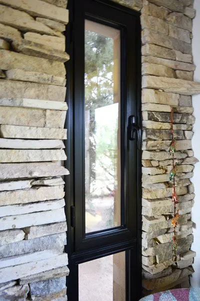Ventana de aluminio negro vidriada entre muros de piedra