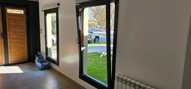 Interior con puerta de PVC Winchester y ventanales negro mate hacia el jardín