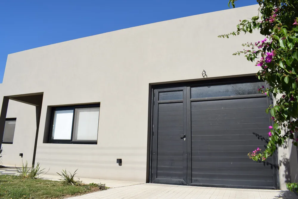 Frente con portón de garaje y ventana de aluminio anodizado negro en General Villegas