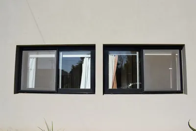 Dos ventanas corredizas de aluminio anodizado negro en la fachada de la vivienda