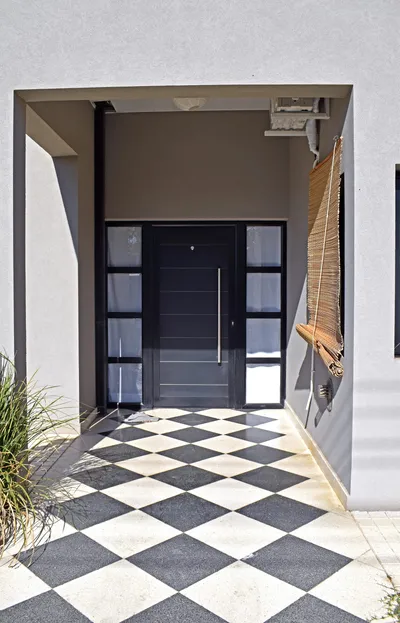 Puerta de entrada de aluminio anodizado negro con paños fijos laterales