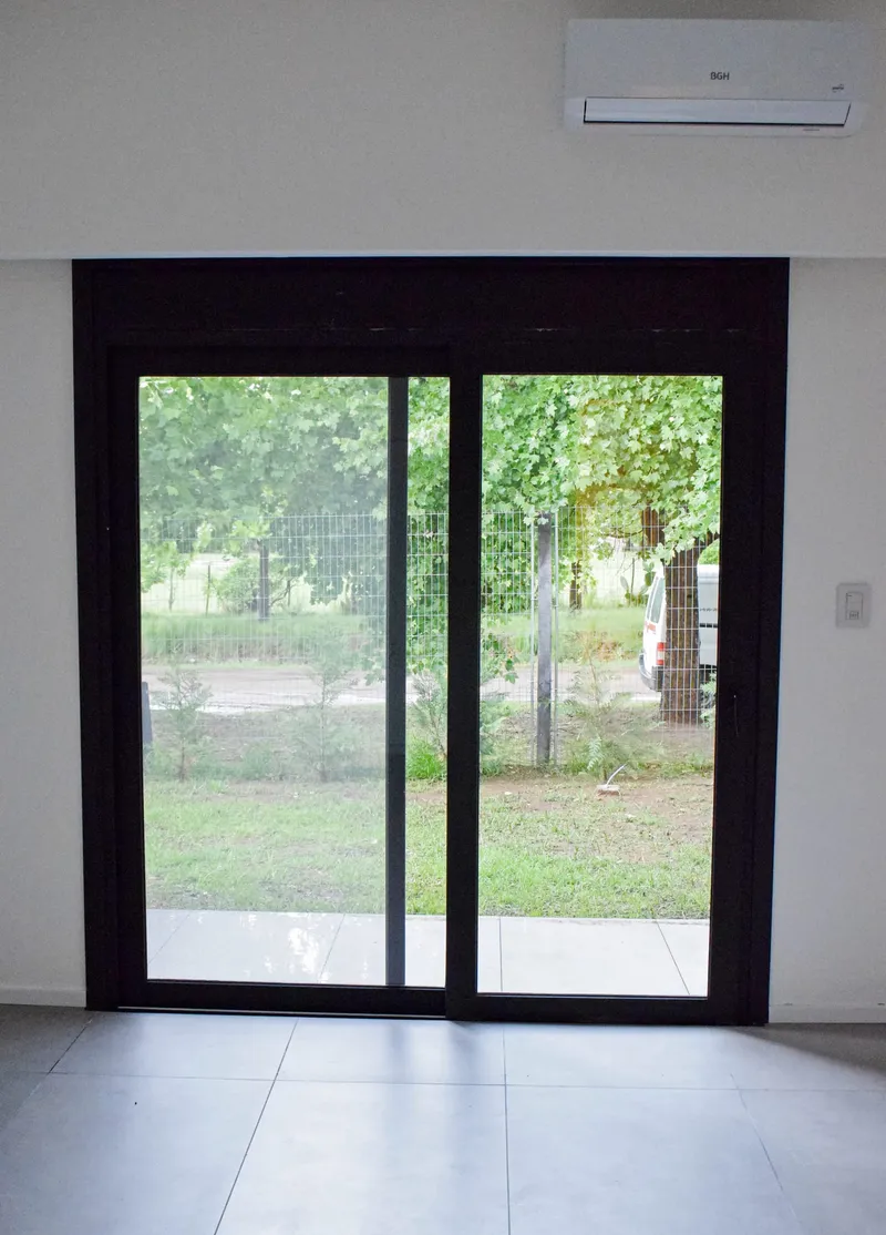 Puerta ventana corrediza de PVC negro mate con salida al jardín