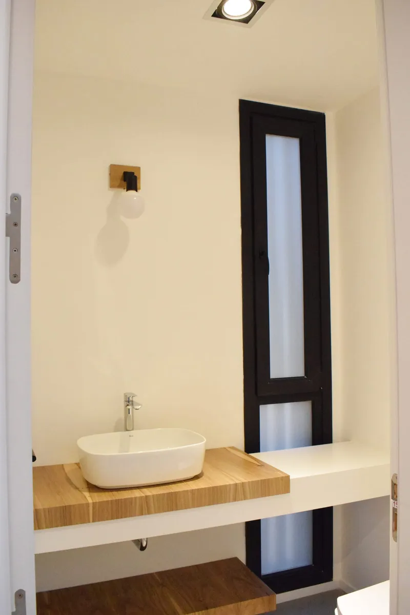Baño con paño fijo vertical de PVC negro mate y vidrio esmerilado