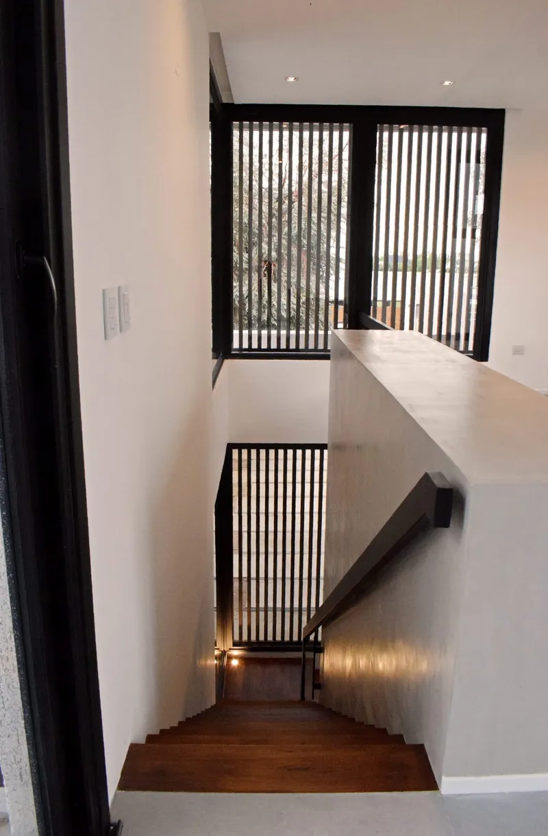 Escalera con paños fijos de PVC negro mate y celosías de madera