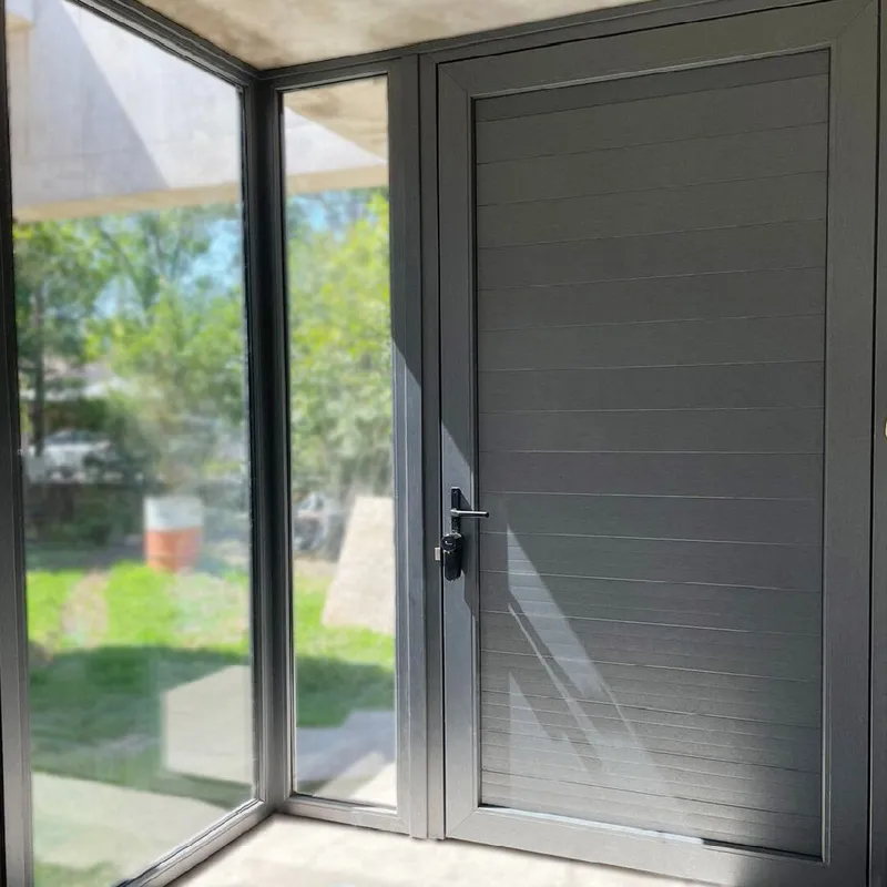 Puerta de PVC Titanium tablillada junto a los paños fijos vidriados de la esquina