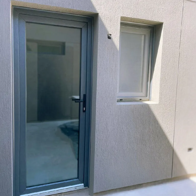 Puerta de PVC Titanium vidriada y ventana de PVC blanco en el lateral de la casa